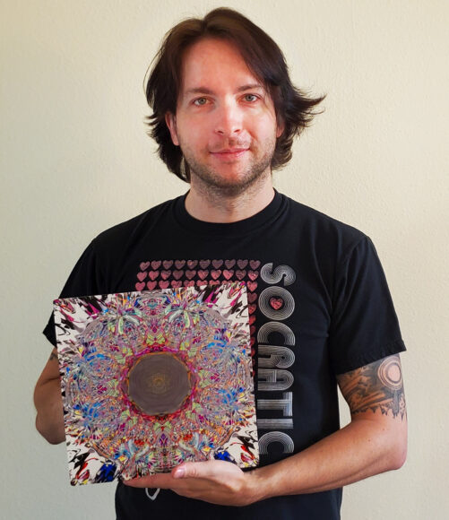 Perplexia artist Ethan J Hulbert holding Radical Difference as a small aluminum print.